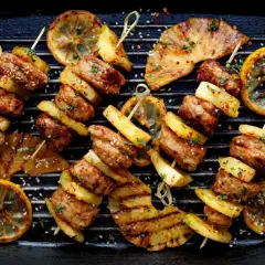 Pyszne mięso na grilla z ananasem i cytryną, posypane sezamem i ziołami, ułożone na grillu.