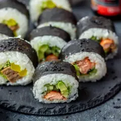 Pyszne domowe sushi z łososiem i awokado, gotowe do podania z imbirem i sezamem.