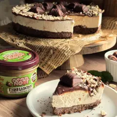 Ciasto kinder bueno z mascarpone, udekorowane orzechami i batonikami. Obok słoik pasty z orzechów laskowych.