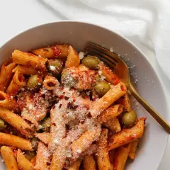 Penne z sosem pomidorowym, oliwkami i startą mozzarellą, posypane płatkami chili.
