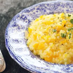 Pyszny, kremowy ryż do risotto z kawałkami dyni, posypany świeżym tymiankiem i pieprzem. Obok leży elegancki widelec.