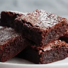Pyszne brownie z airfryer, posypane cukrem pudrem, ułożone na białym talerzu.