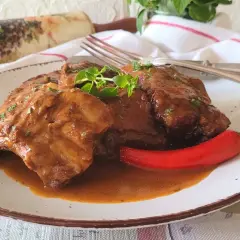 Pyszne, domowe babcine żeberka w sosie własnym, podane z ostrą papryczką i świeżymi ziołami.