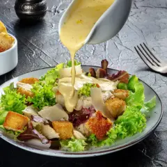 Sałatka cezar oryginalny przepis: chrupiące grzanki, kurczak i parmezan polane kremowym sosem.