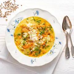 Aromaticzna zupa koperkowa z ryżem, marchewką i kawałkami kurczaka, udekorowana świeżym koperkiem.