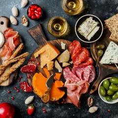 Deska pełna pysznych tapas: sery, wędliny, oliwki, suszone pomidory, grissini, miód i owoce. Idealna na spotkanie.