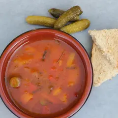Gęsta, pomidorowa solanka z warzywami, podana z chlebem i ogórkami kiszonymi.