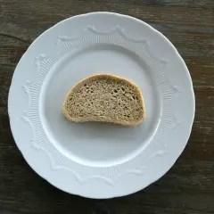 Jeden plasterek chleba na białym talerzu. Zastanawiasz się nad chałka kcal?