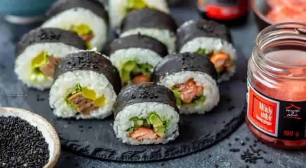 Pyszne domowe sushi z łososiem i awokado, gotowe do podania z imbirem i sezamem.