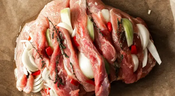 Przygotowanie dania z szynki wieprzowej na obiad. Mięso faszerowane cebulą, papryczką chili i ziołami.