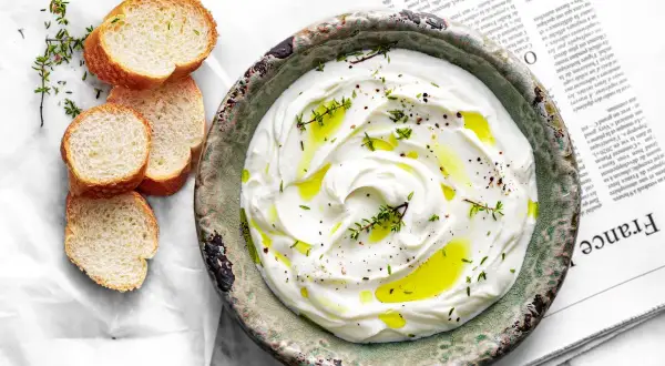 Labneh co to? Kremowy, gęsty serek z jogurtu, skropiony oliwą i ziołami, podany z chrupiącym pieczywem.