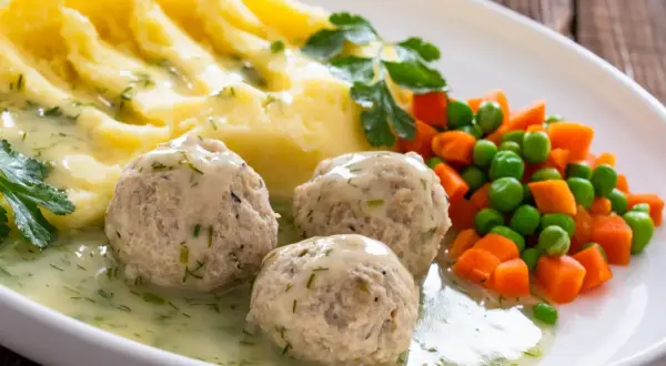 Pyszne klopsiki z mięsa z rosołu w sosie koperkowym, podane z puree ziemniaczanym i warzywami.
