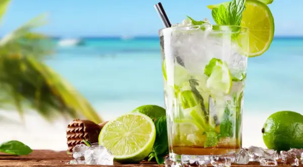 Orzeźwiający mojito bezalkoholowe z limonką i miętą na tle plaży. Idealny na upalne dni.