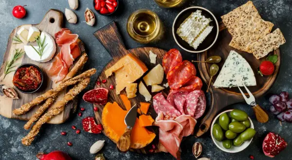 Deska pełna pysznych tapas: sery, wędliny, oliwki, suszone pomidory, grissini, miód i owoce. Idealna na spotkanie.