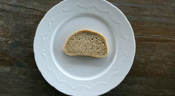 Jeden plasterek chleba na białym talerzu. Zastanawiasz się nad chałka kcal?