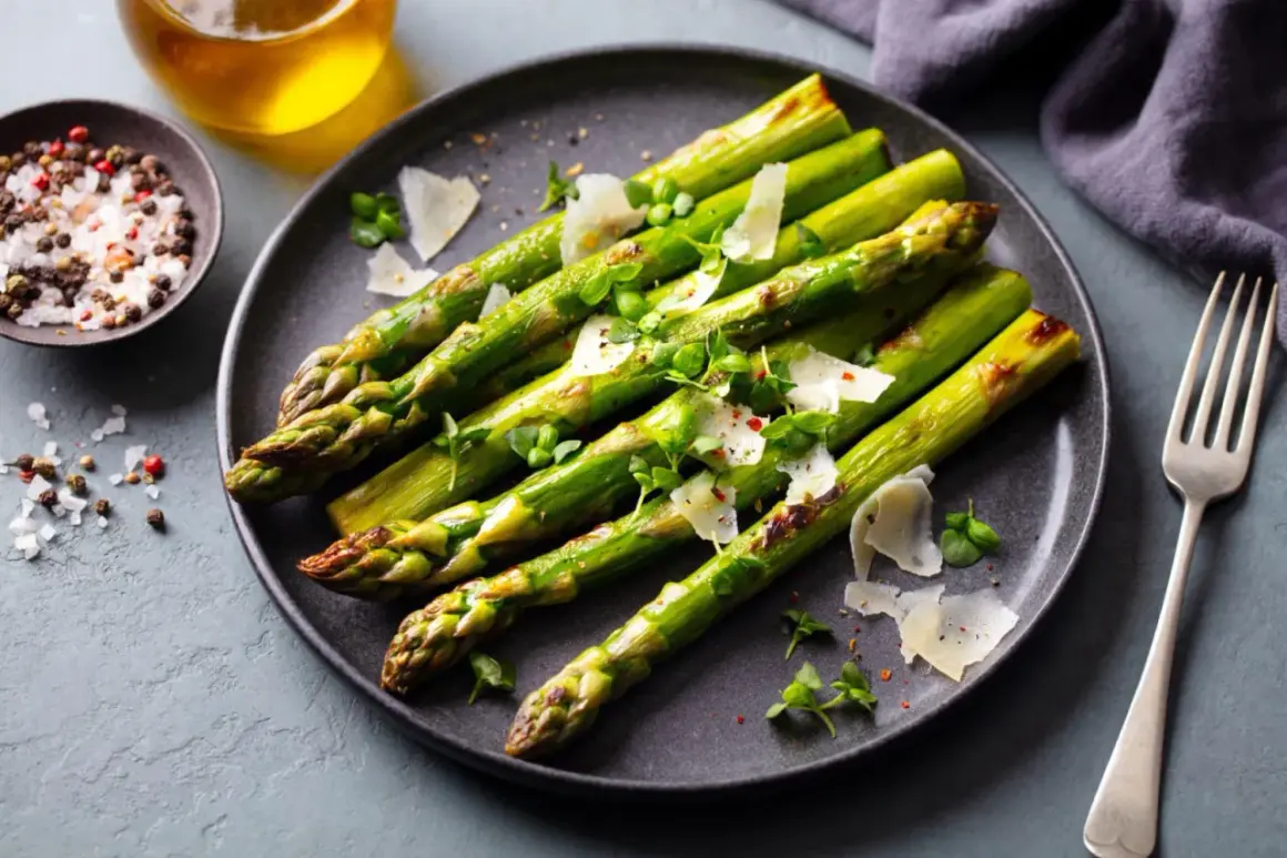 Zielone szparagi z grilla, posypane parmezanem i ziołami, gotowe do podania. Obok miseczka z solą i pieprzem.