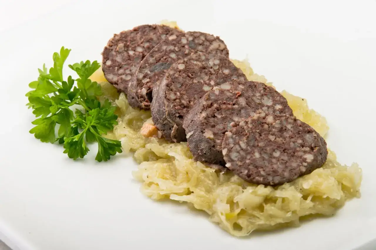 Kiszka pokrojona w plastry, podana na kapuście z natką pietruszki.