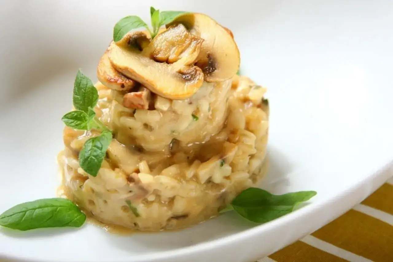 Kremowe risotto z grzybami, udekorowane świeżymi ziołami i plasterkami pieczarek. Idealny ryż do risotto.