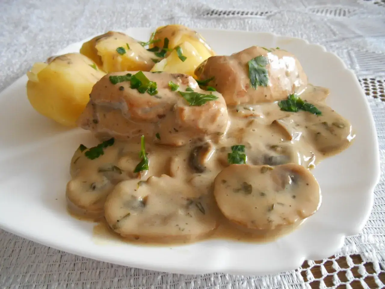 Pyszna pierś z kurczaka w sosie grzybowym z ziemniakami, posypana natką pietruszki.