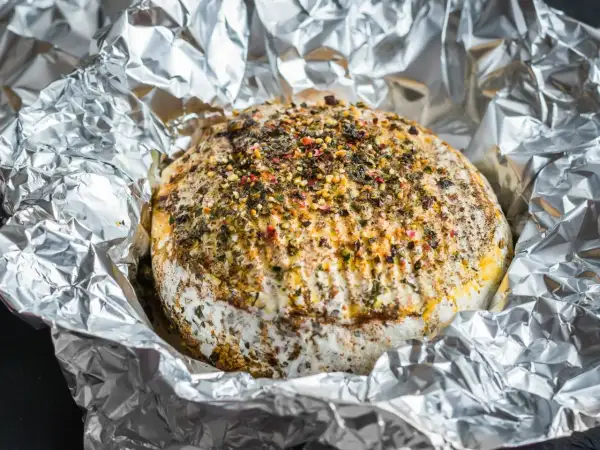 Pyszny camembert z grilla, otulony folią aluminiową, posypany ziołami i przyprawami. Idealny na letnie wieczory.