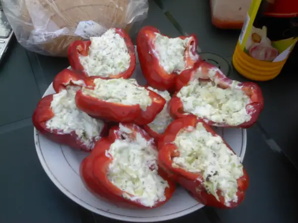 Półłówki czerwonej papryki faszerowane serem i ziołami, gotowe do grillowania.