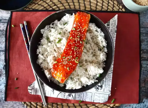 Łosoś w sosie gochujang z sezamem i ryżem, podany z pałeczkami.