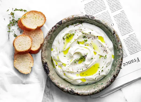 Labneh co to? Kremowy, gęsty serek z jogurtu, skropiony oliwą i ziołami, podany z chrupiącym pieczywem.