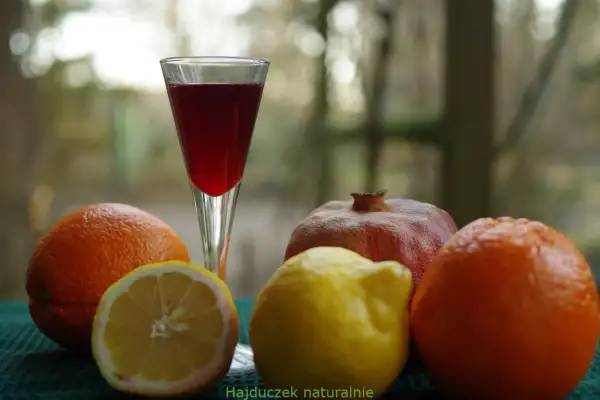Szklanka z czerwonym płynem, obok pomarańcze, cytryna i granat. Czy to grenadyna? Hajduczek naturalnie.