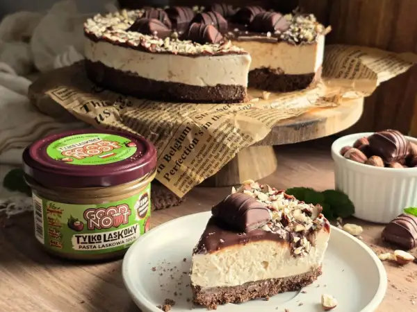 Ciasto kinder bueno z mascarpone, udekorowane orzechami i batonikami. Obok słoik pasty z orzechów laskowych.