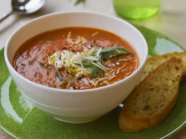 Aksamitna zupa solferino z serem feta i grzankami czosnkowymi na zielonym talerzu.