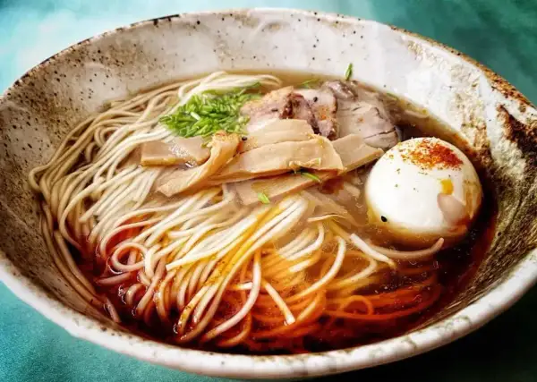 Miseczka zupy ramen z makaronem, jajkiem na twardo, plastrami mięsa i bambusem. Idealny zupa ramen przepis oryginalny.