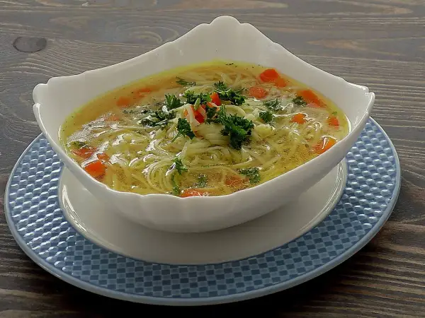 Aromatyczna zupa na rosole z makaronem nitki i marchewką, udekorowana natką pietruszki. Idealna na chłodne dni.