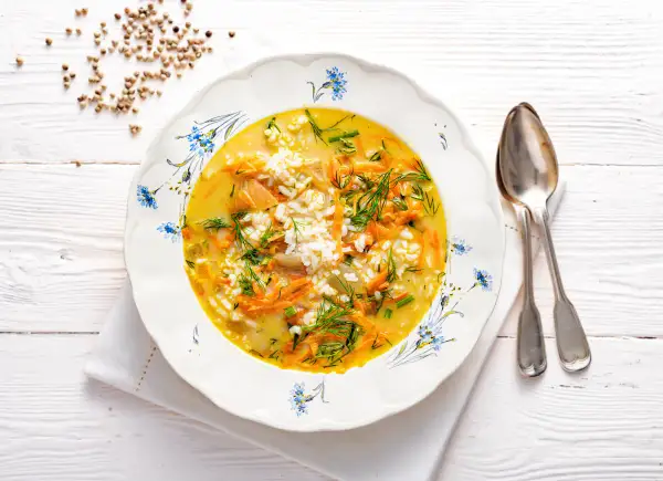 Aromaticzna zupa koperkowa z ryżem, marchewką i kawałkami kurczaka, udekorowana świeżym koperkiem.
