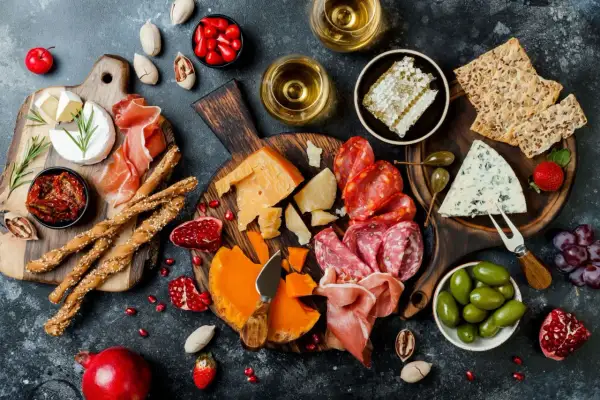 Deska pełna pysznych tapas: sery, wędliny, oliwki, suszone pomidory, grissini, miód i owoce. Idealna na spotkanie.